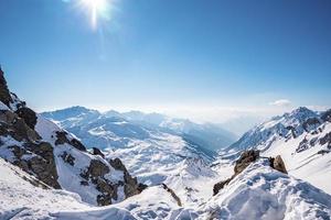 zon schijnt op besneeuwde bergketen tegen lucht foto