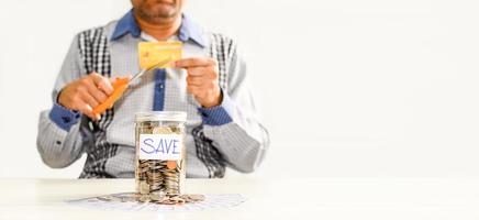 munten en tekst worden opgeslagen in een glazen pot op een houten tafel. concept van geld besparen voor investeringen in de toekomst en niet overbodig, zaken, bankieren, financiën, creditcard, onscherpe achtergrond foto