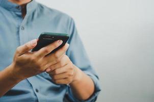 close-up van een man die een mobiele smartphone gebruikt om op internet te zoeken, sms te verzenden, sms-berichten of online banking.copy-ruimte te gebruiken. foto