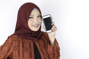 jonge Aziatische islam vrouw lacht met smartphone staande op een witte achtergrond. foto