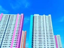 foto van een gebouw in helder wit, oranje, roze en blauw met veel ramen en ook nog een helderblauwe lucht