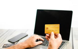 man met creditcard en op laptop toetsenbord te drukken. het concept voor zaken, zaken, online, technologie, internet, kaart, creditcard, betaling, bankieren, financiën, selectieve aandacht, witte achtergrond foto