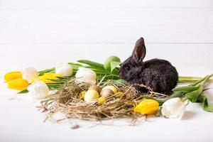 paashaas met paaseieren met tulpen en een nest hooi. positieve lente Pasen samenstelling. foto