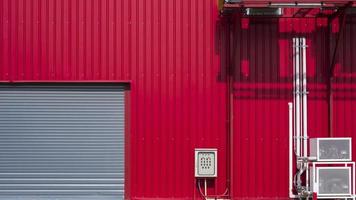 rolluikdeur met hvac-luchtventilatiesysteem met pijpleiding op rode aluminium gegolfde muur van industrieel gebouw foto