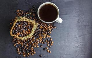 koffiebonen in bruine zak met koffiekopje op zwarte achtergrond. foto