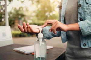 handpers alcoholgel uit de fles en het aanbrengen van ontsmettingsmiddel voor het reinigen van de hand virus covid 19 foto