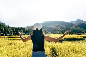 achteraanzicht van reisvrouw ontspannen in de natuur met open arm buiten op dag foto