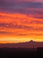 rode zonsondergang met wolken en bergen skyline foto