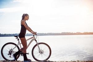 vrouw op een fiets bij het water foto