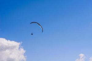 man aan een parachute die in de heldere lucht vliegt foto