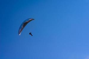 man aan een parachute die in de heldere lucht vliegt foto