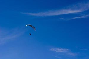 man aan een parachute die in de heldere lucht vliegt foto