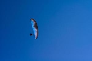 man aan een parachute die in de heldere lucht vliegt foto