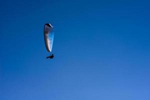 man aan een parachute die in de heldere lucht vliegt foto