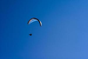 man aan een parachute die in de heldere lucht vliegt foto