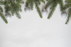 kerst of nieuwjaar compositie. bovenaanzicht, vier zilveren ballen en kerstboom takken op een witte achtergrond, copyspace. foto