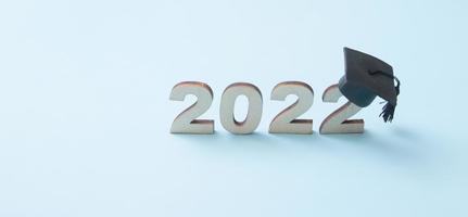 afgestudeerd hoed of pet met houten nummer 2022 op blauwe achtergrond. klasse 2022 concept bannerformaat foto