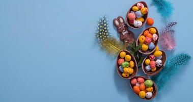 paaseieren jagen concept met plat leggen chocolade-eieren en konijn op blauwe achtergrond. uitzicht van boven foto