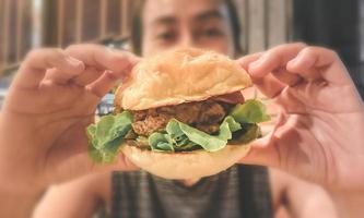 vrouw pick-up hamburger in twee hands.junk food en cholesterol. close-up en vervagen. foto