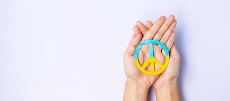 steun voor oekraïne in de oorlog met rusland, handen met symbool van vrede met vlag van oekraïne. bid, geen oorlog, stop oorlog, sta achter Oekraïne en nucleaire ontwapening foto