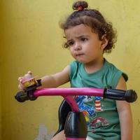 schattige kleine jongen shivaay fietsen op het balkon thuis tijdens de zomer, lieve kleine jongen fotoshoot overdag, kleine jongen geniet van fietsen thuis tijdens fotoshoot foto