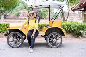 een niet-geïdentificeerde vrouw die op een ouderwetse auto zit, gebruikt als shuttle-voertuigen voor toeristen foto