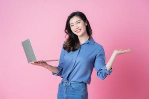 jonge Aziatische zakenvrouw met behulp van laptop op roze achtergrond foto