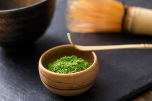 groene matcha-thee bereidt zich voor op steenzwarte tafel foto