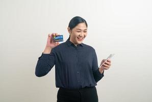 Aziatische vrouw die smartphone gebruikt met de hand met creditcard foto