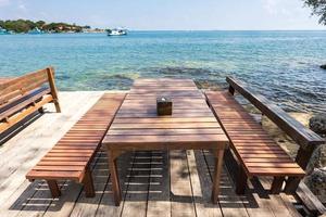 terras zeezicht met houten buitenstoelen en tafel