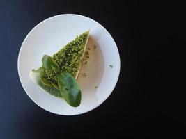 groene thee cheesecake op witte plaat op zwarte tafel achtergrond foto