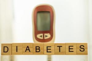 close-up van houten letters blok formulering en glucose meter als achtergrond gebruiken als geneeskunde, diabetes, glycemie, gezondheidszorg en mensen concept. foto