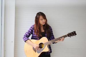 een jonge mooie vrouw speelt gitaar. foto