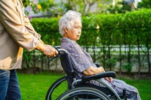 Aziatische oudere vrouw handicap patiënt zittend op rolstoel in park, medisch concept. foto