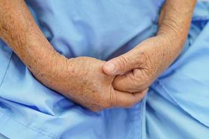 Aziatische oudere senior vrouw patiënt legde hand in hand alleen op haar schoot foto