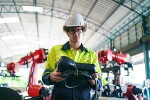 industrieel ingenieur of werknemer die een helm draagt terwijl hij in een zware industriële fabriek staat. het onderhoud van het werken aan industriële machines en het controleren van de installatie van het beveiligingssysteem in de fabriek. foto