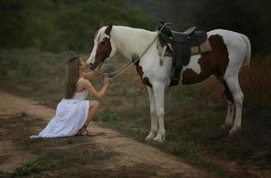 jonge vrouw met haar paard in avondzonsonderganglicht. buitenfotografie met fotomodel meisje. levensstijl stemming foto