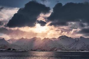 zonsondergang in bewolkt op besneeuwde bergketen op het eiland Senja foto