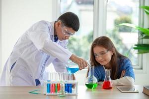 studenten mengen chemicaliën in bekers. scheikundestudent mengt chemicaliën in de natuurkundeles foto