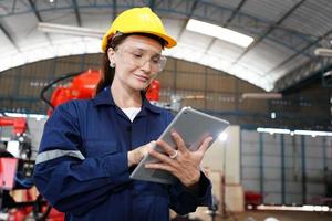 portret van een professionele ingenieur in de zware industrie met uniform, bril en helm in een staalfabriek. mooie vrouwelijke industriële specialist permanent in metalen constructie faciliteit. foto