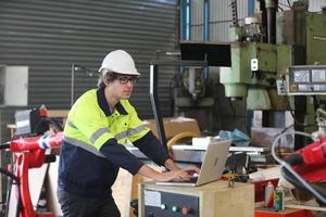 professionele industriële fabrieksmedewerker die met machineonderdelen werkt, industriële apparatuur en robotarmen controleert en test in een grote fabriek voor elektrische elektronica, draad- en kabelfabriek foto