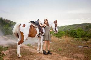 jonge vrouw met haar paard in avondzonsonderganglicht. buitenfotografie met fotomodel meisje. levensstijl stemming foto