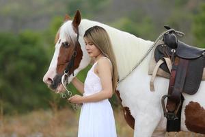 jonge vrouw met haar paard in avondzonsonderganglicht. buitenfotografie met fotomodel meisje. levensstijl stemming foto