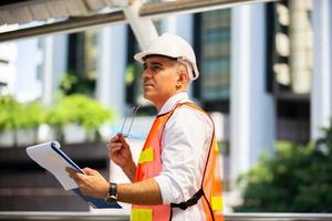 de ingenieur die op het klembord controleert bij de bouw van de bouwplaats. het concept van engineering, constructie, stadsleven en toekomst. foto