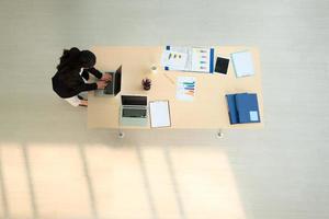 bovenaanzicht zakenvrouw met behulp van laptop op bureau in het kantoor. foto