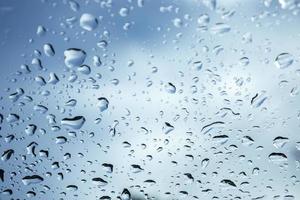 regendruppels op glas blauwe lucht en somber weer mooie hemelachtergrond foto