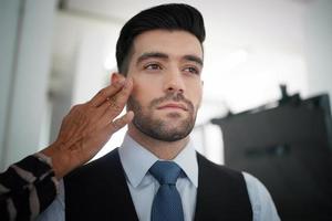 portret van knappe man was make-up door kunstenaar op zijn gezicht. foto