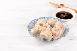 vers, heerlijk gekookt varkensvlees gyoza dumplings, jiaozi op witte achtergrond met sojasaus en eetstokjes, close-up, levensstijl. zelfgemaakte ontwerpconcept. foto