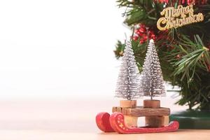 versierde schattige kerstboom op een houten vloer met witte achtergrond en speelgoed, leeg voor feestelijk ontwerpconcept, close-up. foto