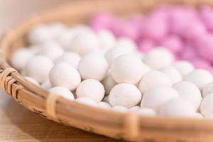 een Aziatische vrouw maakt tang yuan, yuan xiao, chinese traditionele rijstknoedels in rood en wit voor nieuw maanjaar, winterfestival, close-up. foto